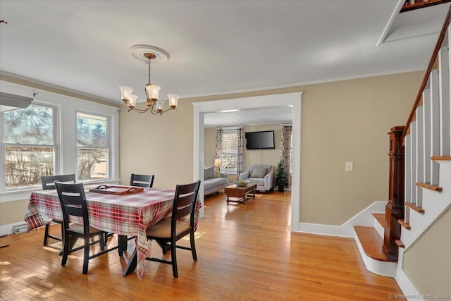 dining area featuring baseboards, light wood-style floors, stairs, and crown molding