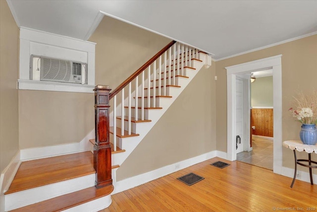 staircase featuring hardwood / wood-style floors, baseboards, visible vents, and ornamental molding