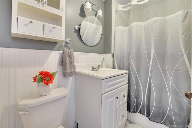 bathroom with a shower with curtain, wainscoting, vanity, and toilet