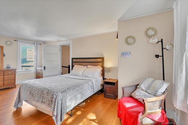 bedroom featuring crown molding and light wood finished floors