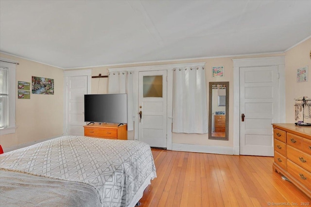 bedroom featuring light wood finished floors, baseboards, and ornamental molding