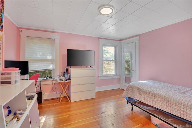 bedroom with multiple windows, light wood-type flooring, and ornamental molding