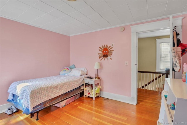 bedroom with crown molding, light wood-type flooring, and baseboards