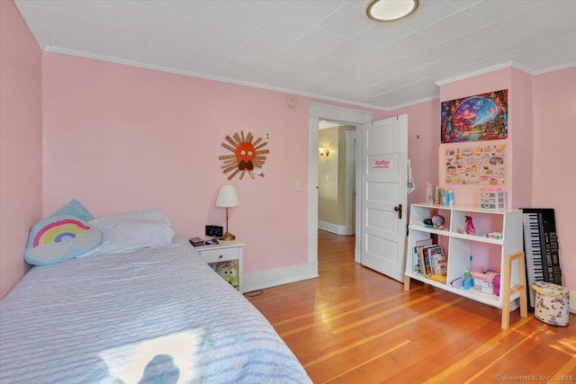 bedroom with baseboards, light wood finished floors, and ornamental molding