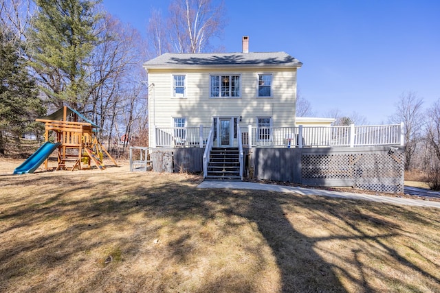 back of house with a lawn, a chimney, and a playground