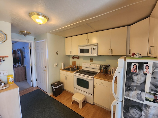 kitchen featuring light countertops, white appliances, light wood-type flooring, and a sink