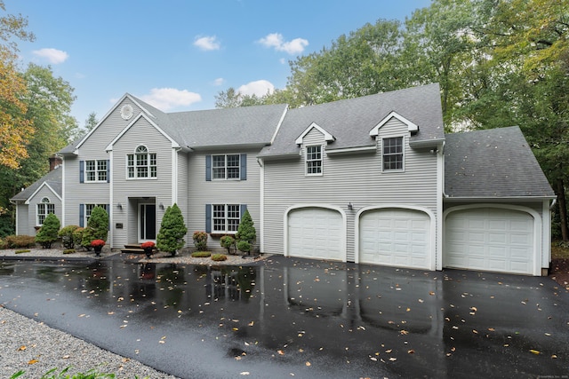 view of front facade with a garage, roof with shingles, and driveway