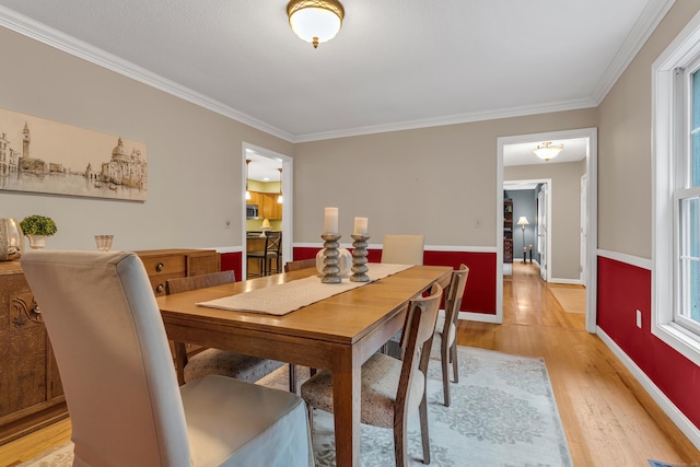 dining space featuring light wood-style flooring, baseboards, and ornamental molding