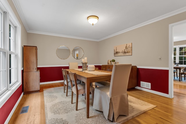 dining space with visible vents, baseboards, light wood-style floors, and ornamental molding