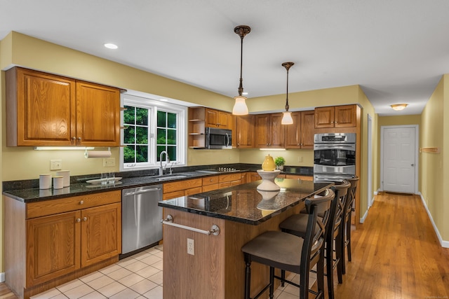 kitchen featuring a kitchen island, a sink, appliances with stainless steel finishes, a kitchen breakfast bar, and brown cabinets