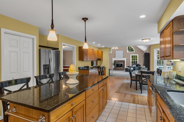 kitchen featuring open floor plan, appliances with stainless steel finishes, a fireplace, light tile patterned flooring, and open shelves