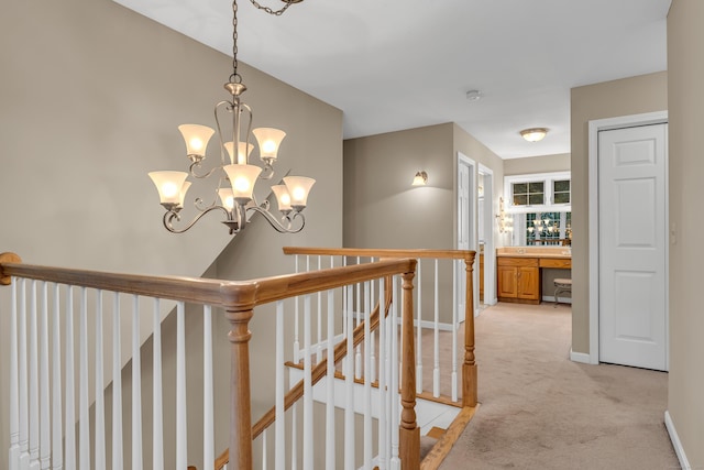 hallway with an upstairs landing, a chandelier, light colored carpet, and baseboards