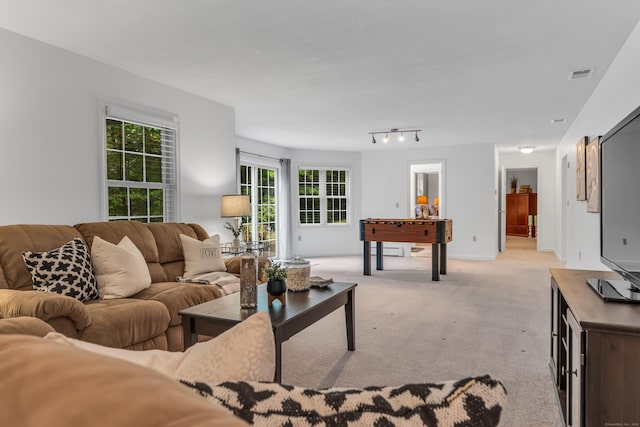 living area featuring light carpet, visible vents, rail lighting, and baseboards