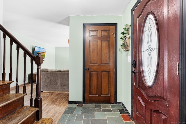 entrance foyer featuring dark wood-style floors, stairway, and baseboards