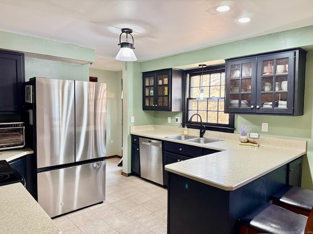 kitchen with appliances with stainless steel finishes, light countertops, a sink, and a peninsula