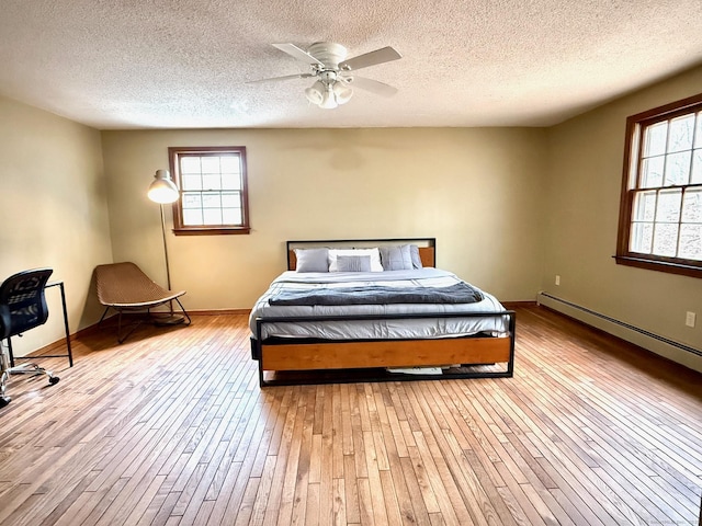 bedroom with a textured ceiling, hardwood / wood-style floors, baseboard heating, and baseboards