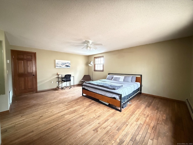 bedroom with baseboards, ceiling fan, a textured ceiling, and hardwood / wood-style floors