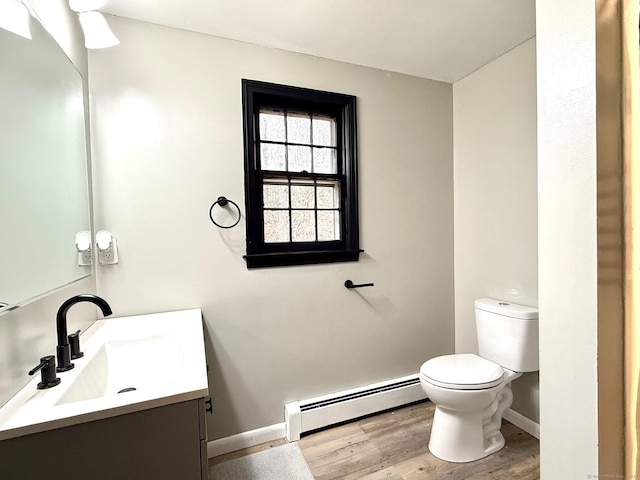 bathroom featuring a baseboard radiator, toilet, wood finished floors, vanity, and baseboards