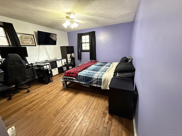 bedroom with a textured ceiling, ceiling fan, and wood-type flooring