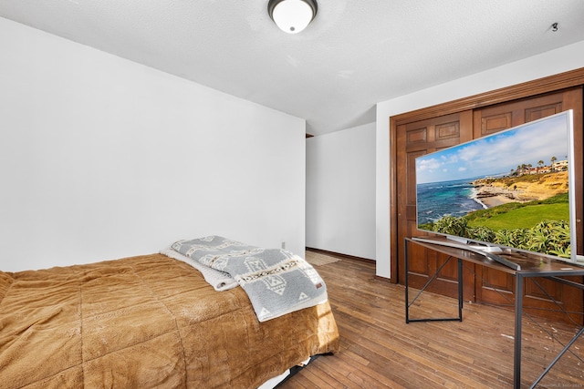 bedroom featuring a textured ceiling, baseboards, and hardwood / wood-style flooring