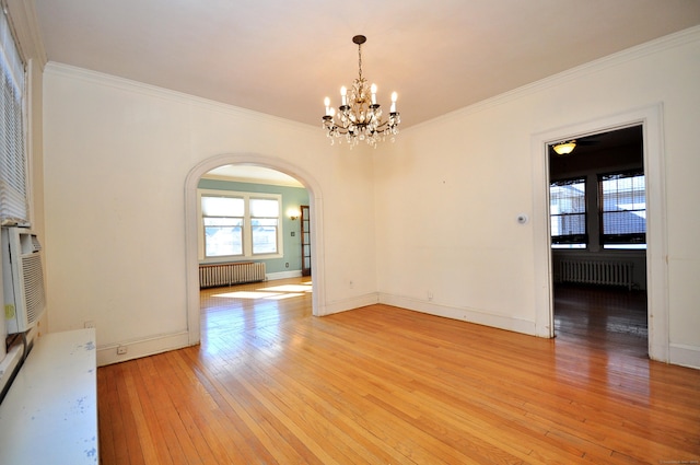 unfurnished dining area with arched walkways, radiator, light wood-style flooring, and ornamental molding