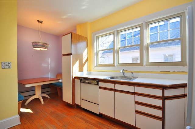 kitchen with a sink, white cabinetry, light wood-style floors, white dishwasher, and hanging light fixtures