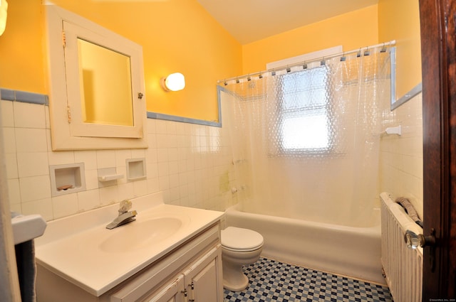 full bathroom with vanity, shower / bathtub combination with curtain, radiator heating unit, tile walls, and toilet