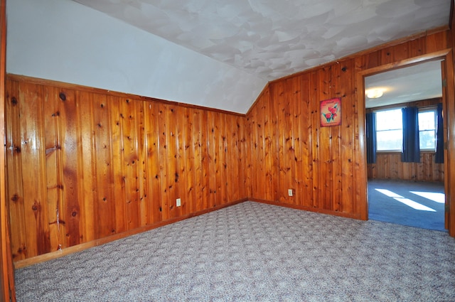 additional living space with wood walls, carpet, and vaulted ceiling