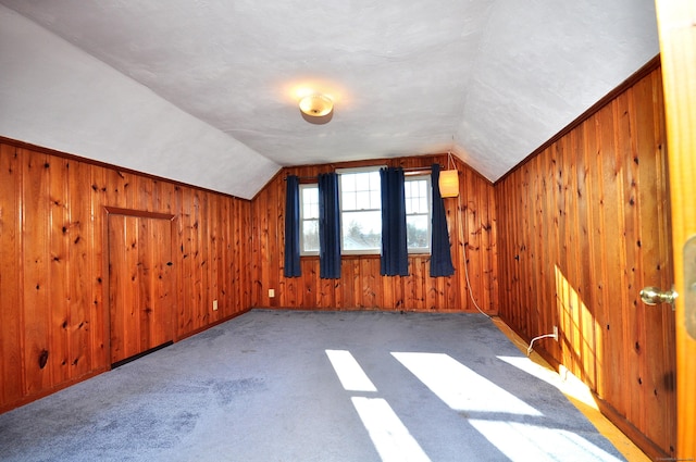 bonus room featuring wood walls, carpet, and vaulted ceiling