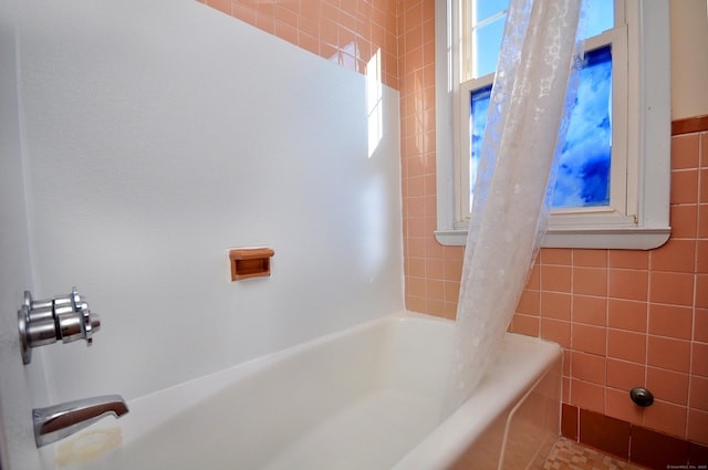 bathroom featuring shower / bathtub combination with curtain and tile walls