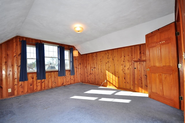 bonus room featuring wood walls, lofted ceiling, and carpet floors