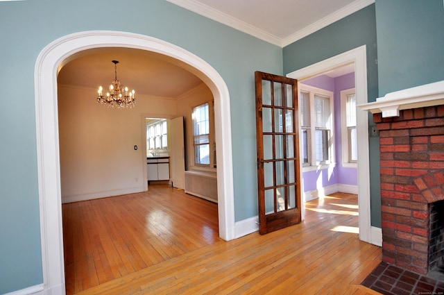 unfurnished dining area with a healthy amount of sunlight, a fireplace, wood-type flooring, and ornamental molding