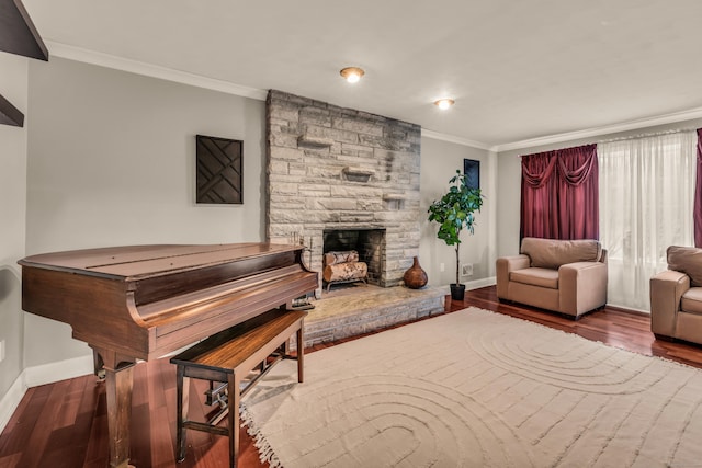 living room with baseboards, wood finished floors, a fireplace, and crown molding