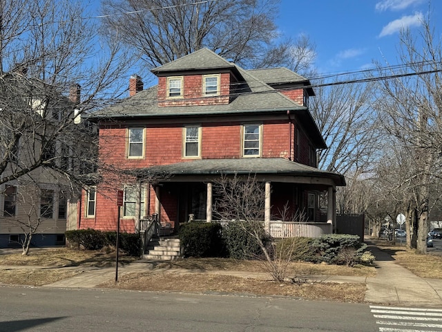 traditional style home featuring covered porch, a shingled roof, and a chimney