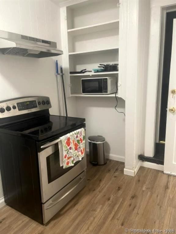 kitchen featuring under cabinet range hood, stainless steel electric range oven, baseboards, and wood finished floors