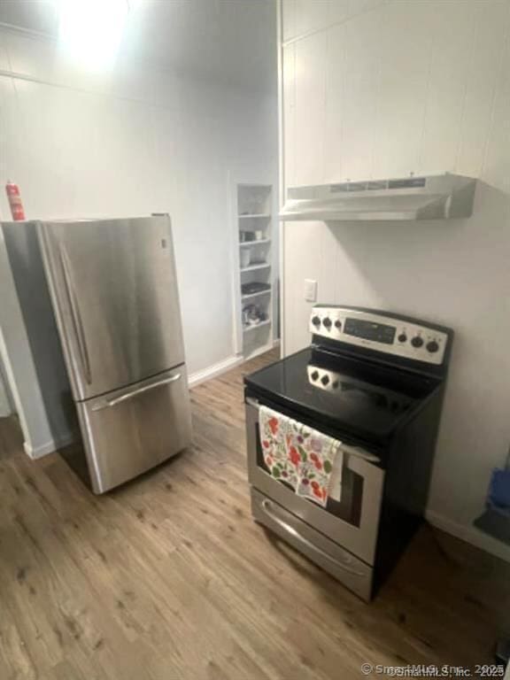 kitchen featuring light wood-style flooring, under cabinet range hood, white cabinetry, stainless steel appliances, and baseboards