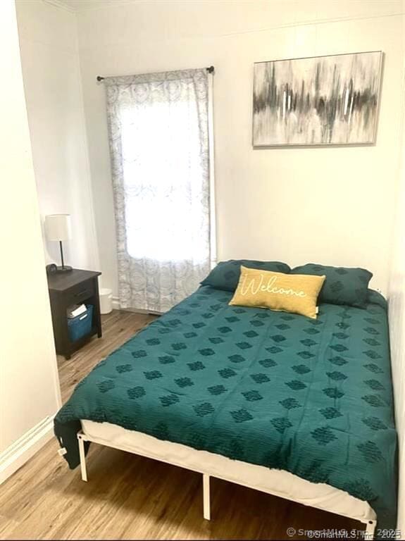 bedroom featuring baseboards and wood finished floors