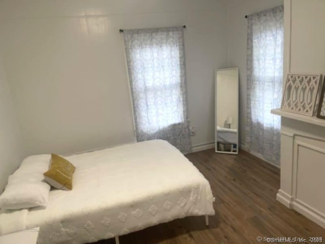 bedroom with multiple windows and dark wood-type flooring