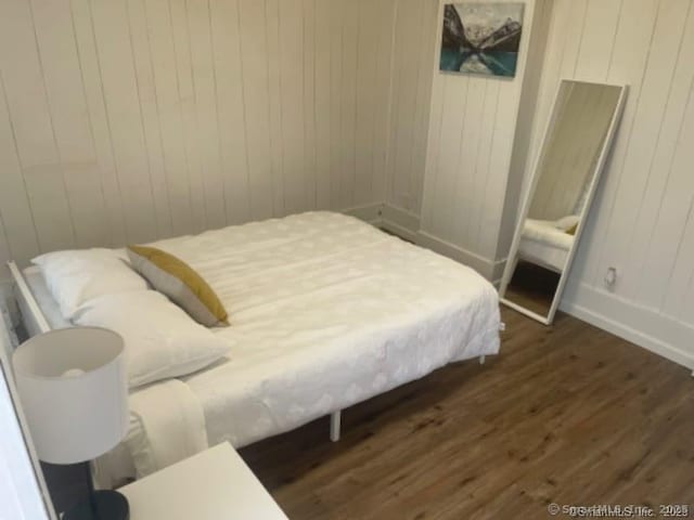 bedroom with baseboards and dark wood-type flooring