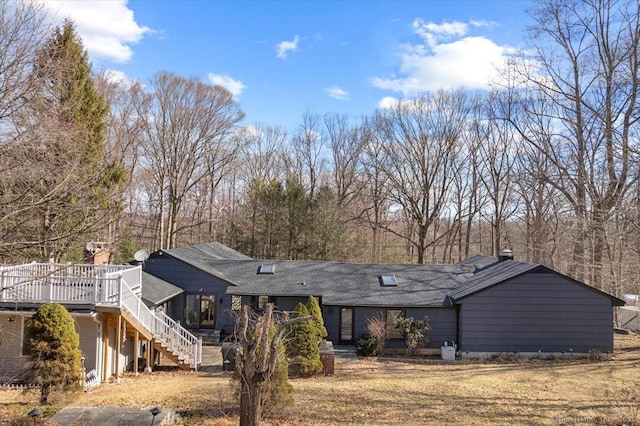 view of front facade with a front yard, stairway, and a wooden deck