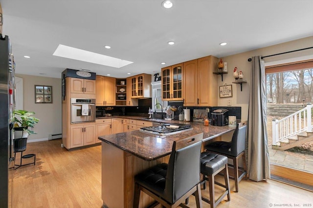 kitchen with a peninsula, a skylight, a sink, stainless steel appliances, and a kitchen breakfast bar