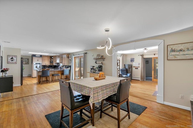 dining room featuring a baseboard heating unit, baseboards, visible vents, and light wood-style flooring