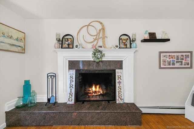 interior details featuring a baseboard radiator, wood finished floors, and a tiled fireplace