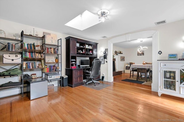 home office with visible vents, a skylight, and light wood finished floors