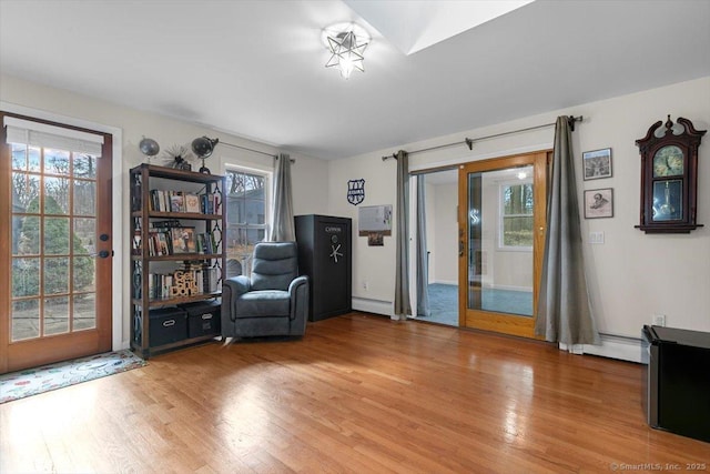 sitting room featuring light wood-style flooring, french doors, and a baseboard heating unit