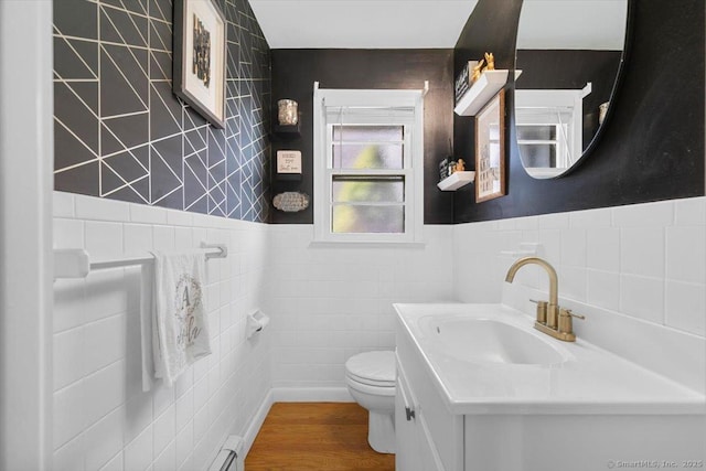 bathroom featuring tile walls, a wainscoted wall, toilet, wood finished floors, and vanity