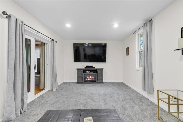 unfurnished living room featuring recessed lighting, baseboards, carpet floors, and a lit fireplace