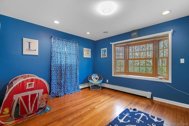 interior space with a baseboard heating unit, recessed lighting, baseboards, and wood-type flooring