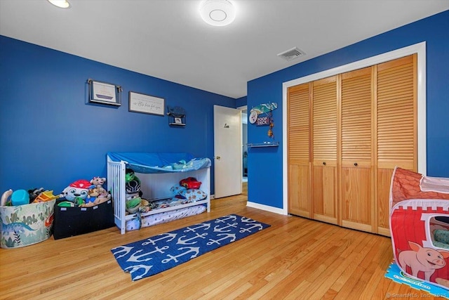 bedroom featuring a closet, visible vents, baseboards, and wood finished floors