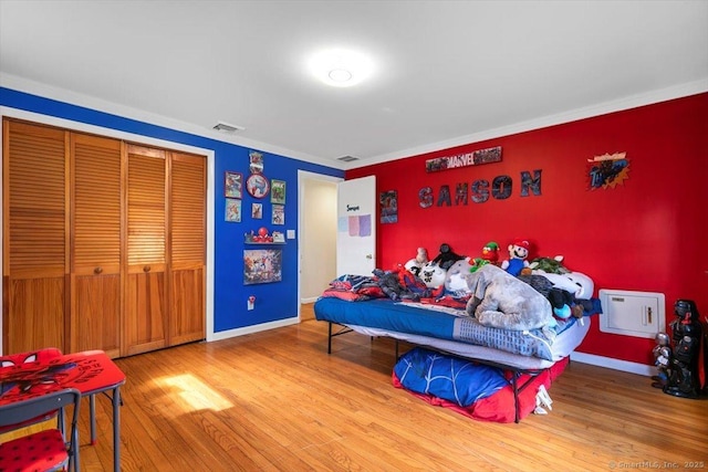 bedroom with visible vents, baseboards, a closet, and wood finished floors